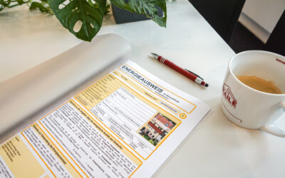 Ein offener Energieausweis auf einem weißen Schreibtisch, begleitet von einer Maile Immobilien Stuttgart-Tasse und einem Stift